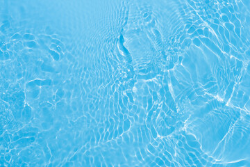 Blue water with ripples on the surface. Defocus blurred transparent blue colored clear calm water surface texture with splashes and bubbles. Water waves with shining pattern texture background.