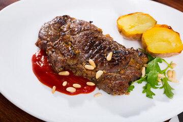Barbecue rib steak served with ketchup, pine nuts and arugula