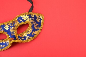 One beautiful carnival mask on red background, top view. Space for text