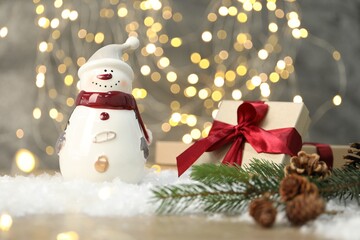 Funny snowman figure and other decor on table against blurred lights