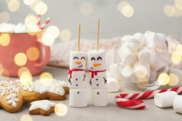 Funny snowmen made of marshmallows and other sweets on light table