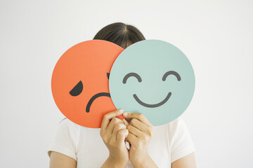 Woman hands holding sad face hiding behind happy face, bipolar and depression, mental health, split...