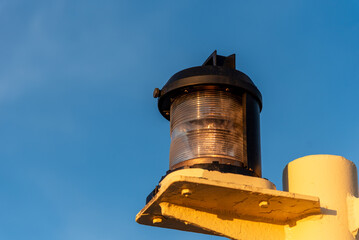 Close-up of navigation lights on a large cargo ship, the lamps standing out sharply against the clear blue sky. The detail captures the essential maritime equipment.