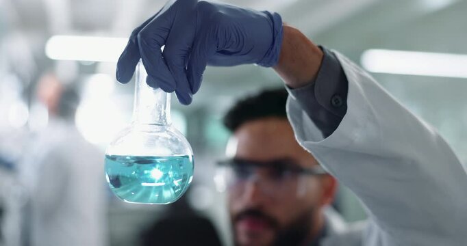 Scientist, beaker and chemical shake in laboratory, man and experimental chemistry for research. Formulation, cure innovation and reaction observation, safety gloves and breakthrough study for career