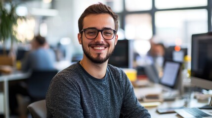 Obraz premium Young happy engineer man in startup, working enthusiastically in a vibrant, modern office, surrounded by innovative projects and a dynamic, entrepreneurial atmosphere.