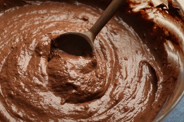 Chocolate dough and spoon in bowl, closeup