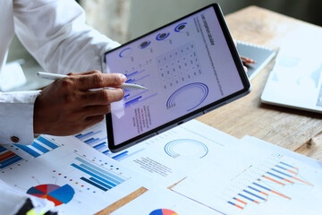 A 29-year-old businessman working hard to analyze company expense documents using a tablet.