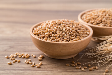 Whole wheat grain in wooden bowl on wooden background, Food ingredient