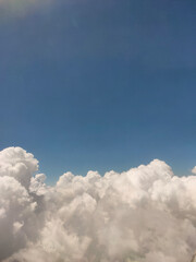 Close up photo of fluffy white cumulus clouds in a blue sky with copy space image