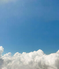 Close up photo of fluffy white cumulus clouds in a blue sky with copy space image