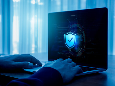 Cybersecure, wifi internet network security technology, privacy digital data protection concepts. Safety shield icon hologram appears while person hands work with laptop computer, blue tone.