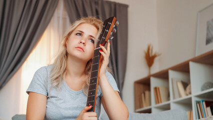 Upset woman. Guitar player. Depressed mood. Sad frustrated lady holding musical instrument feeling romantic sitting light room interior.