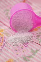 Washing powder in plastic spoon on blue background 