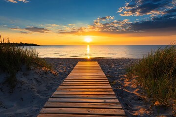 Fototapeta premium Wooden pathway through sandy dunes leading to a scenic beach sunset with calm waves and clear skies.