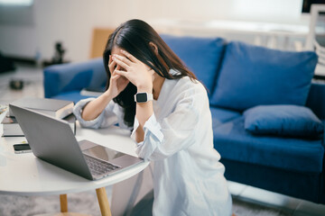 Young asian woman is experiencing stress and burnout while working from her home office. She is...