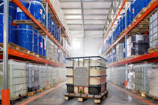Chemical factory warehouse. Hangar interior with barrels on racks. Industrial building for storing chemicals. IBC container between warehouse shelves. Storage with chemical liquids in tanks. 