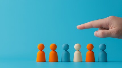A hand pointing at diverse colored figurines on a blue background, symbolizing selection, decision, or leadership methods.