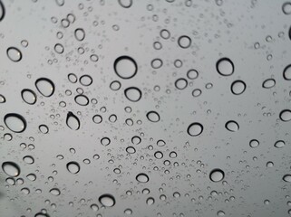 Raindrops, water droplets settle on the glass. There is a blurry image in the background.