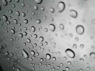Raindrops, water droplets settle on the glass. There is a blurry image in the background.
