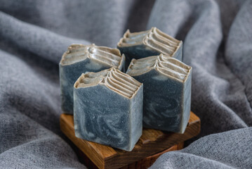 Natural black and white handmade soap on a wooden soap dish on a background of gray fabric