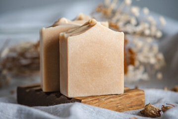 Delicate natural soap in pastel colors on a wooden soap dish on a background of gray fabric