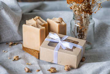 Cute pieces of craft natural soap and a gift box with a white ribbon on a fabric background