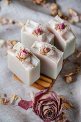 Delicate pieces of natural floral soap decorated with rosebuds in a wooden soap dish. A beautiful postcard