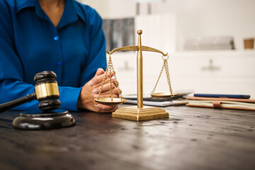 An Asian female lawyer sits at her desk in the office,working on legal documents with computer,providing online legal consulting,reviewing contracts,drafting wills,offering signature certification