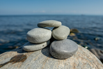 Handmade soap pieces in the shape of stones are stacked on top of each other on the shore of the sea or lake. Image of organic cosmetics in a natural environment