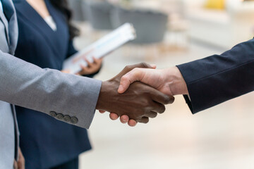 Close-Up of Business Handshake Between Diverse Professionals with Colleague in Background