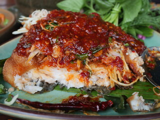 Traditional deep fried fish fillet dressing with special chilly dipping sauce serving on the plate. Famous seafood menu in Asian restaurant. 