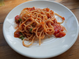Traditional spaghetti with red sauce dressing with tomato serving on the plate. Famous Italian noodle menu in restaurant. 