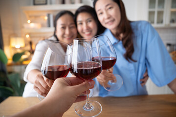 Senior middle aged Women Asian friends talking and holding wine glasses and smile take a selfie in kitchen. Reunion friendship greeting concept