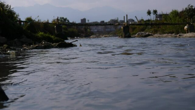Water flowing in a river with an old bamboo bridge made by locals 