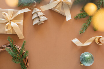 Festive composition of Christmas ornaments, fir branch, wrapped gift, lights on a beige background with copy space.