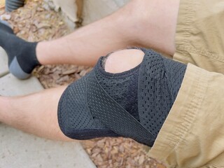 Black knee brace wrap on man's left leg.
