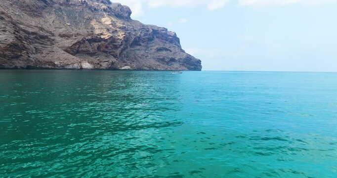 Boat And Pod Of Swimming Dolphins Near Shore of Shoab On Socotra Island In Yemen. wide shot