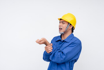 Young male construction worker in blue coveralls holding his injured wrist. Safety risks and work-related injury concept on a white background.