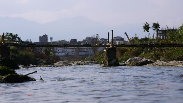 local made old bamboo bridge on a flowing river water.