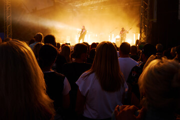 Silhouettes of crowd at concert in front of stage with bright spotlights. People enjoy live music...