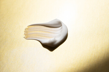 White cosmetic cream smear gold background