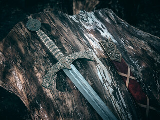A beautiful medieval sword with a bronze hilt and red scabbard.