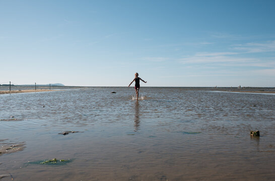 girl running into shallow water in the sea at Sk&aring;ne, Sweden