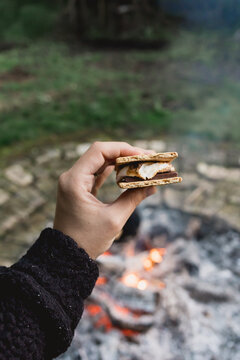 Young woman assembling a toasted s'more at an outdoor gathering