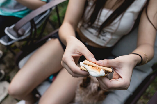 Young woman assembling a toasted s'more at an outdoor gathering