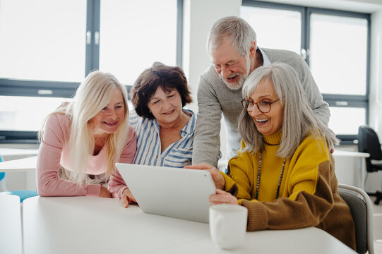 Group of senior students looking at tablet screen, learning new skill. Elderly people attending computer and technology education class. Digital literacy.