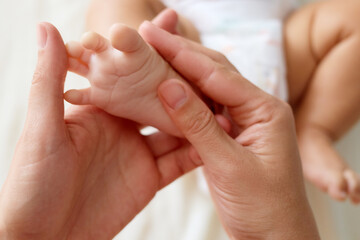 Unrecognizable anonymous mother gently doing massage on her cute unknown baby foot prevention of flat feet development muscle tone and dysplasia