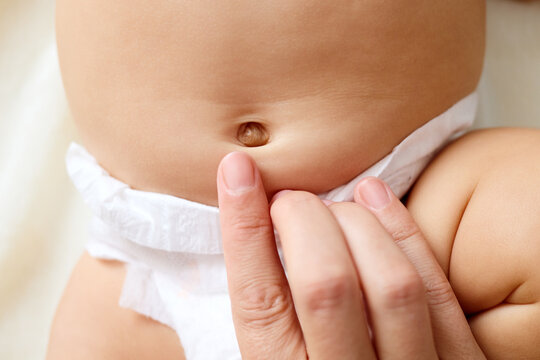 Unrecognizable woman gentle mother touching her baby navel with her finger