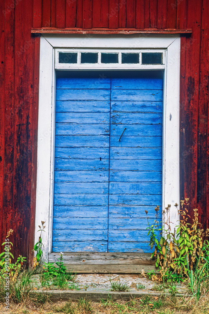 Poster Blue door on an old red wooden cottage