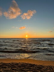 Sunset over the ocean with gentle waves on the shore.